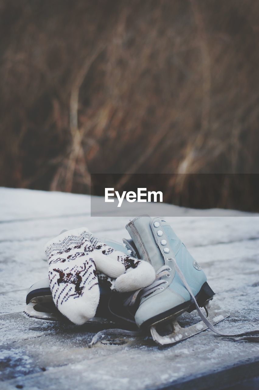 Ice skates with gloves on snow covered field