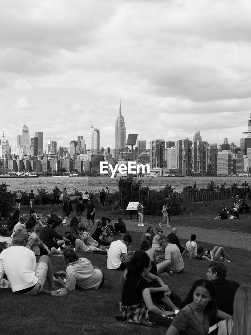 PEOPLE SITTING BY BUILDINGS AGAINST SKY