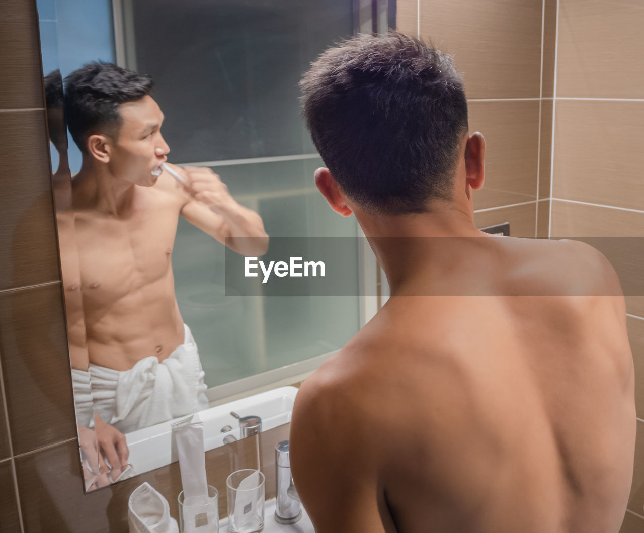 Rear view of shirtless man standing in bathroom