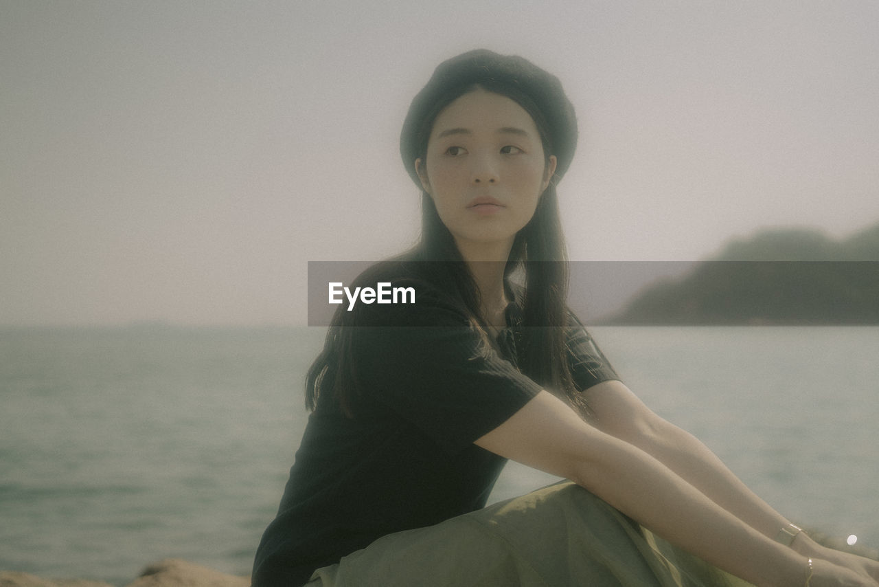 PORTRAIT OF BEAUTIFUL WOMAN STANDING AGAINST SEA