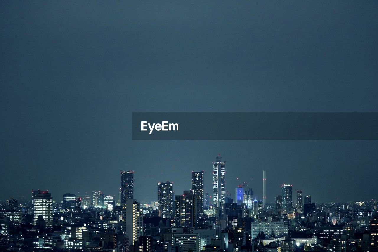 Illuminated buildings in city against sky at night