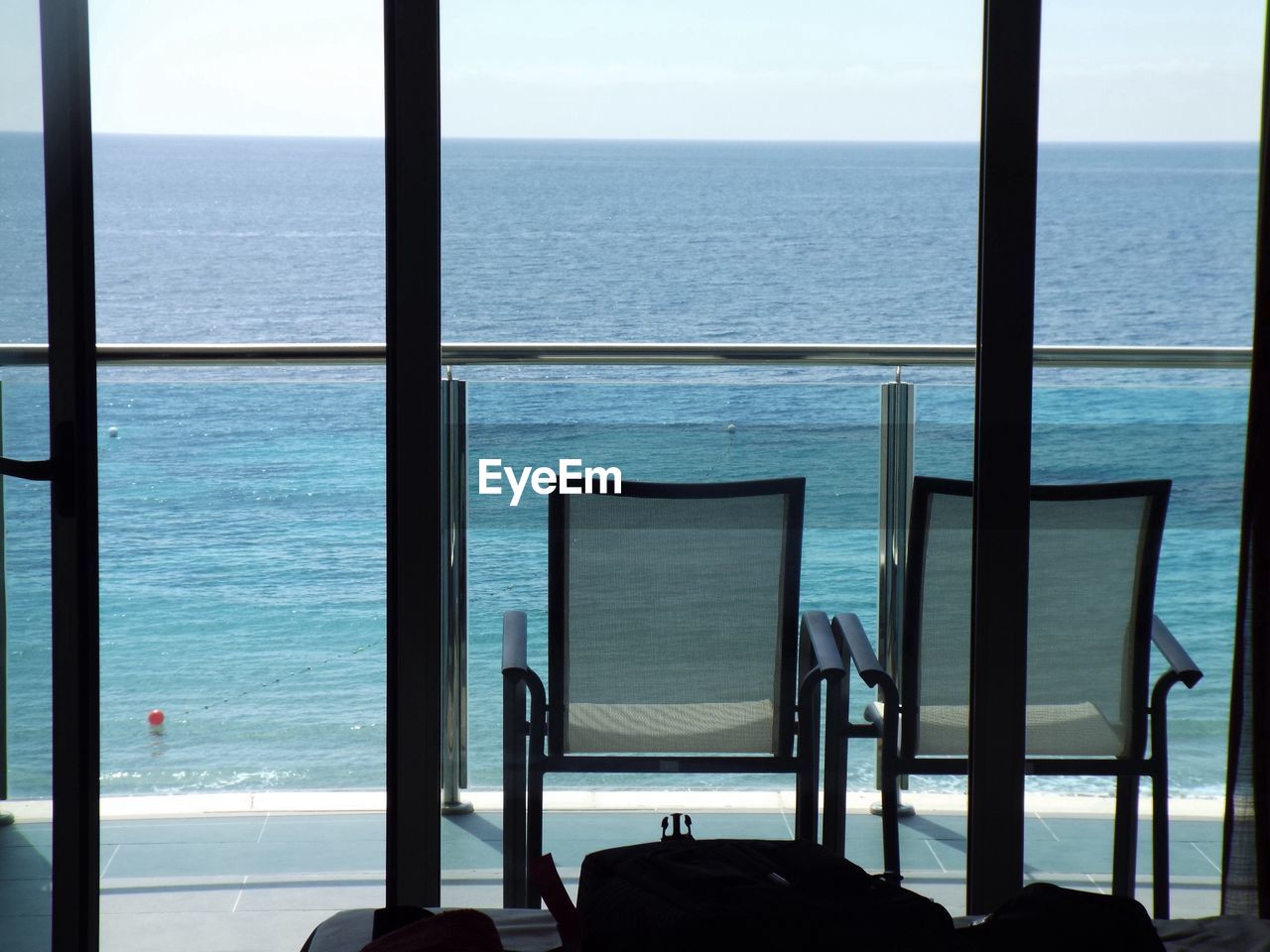 Two empty chairs on seafront balcony