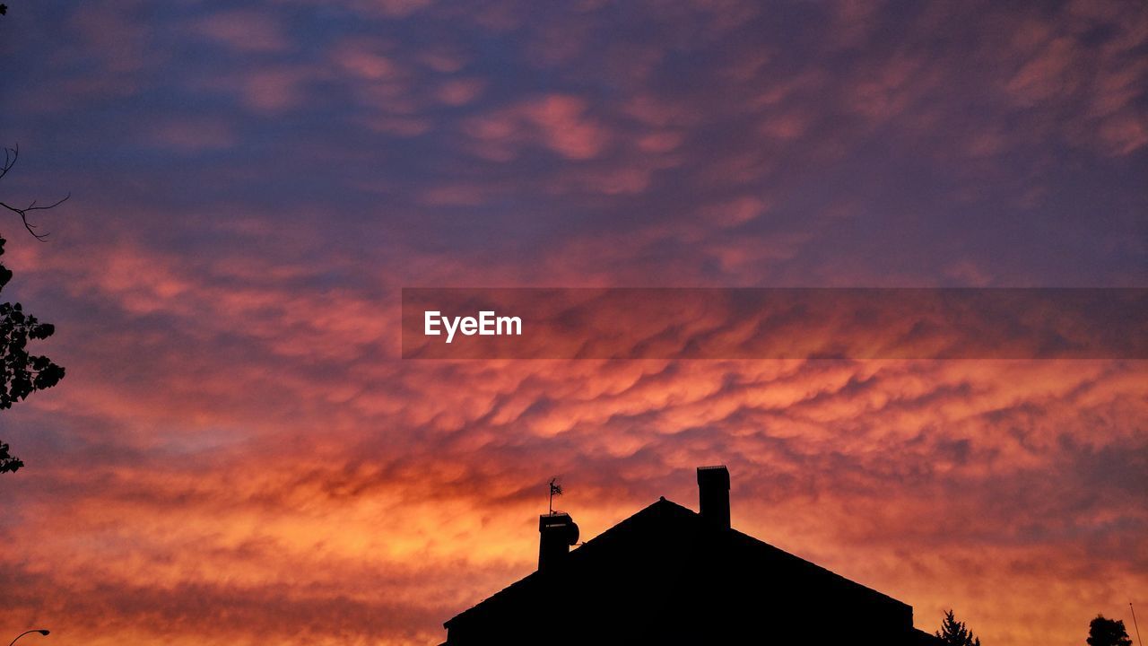 Low angle view of silhouette building against orange sky