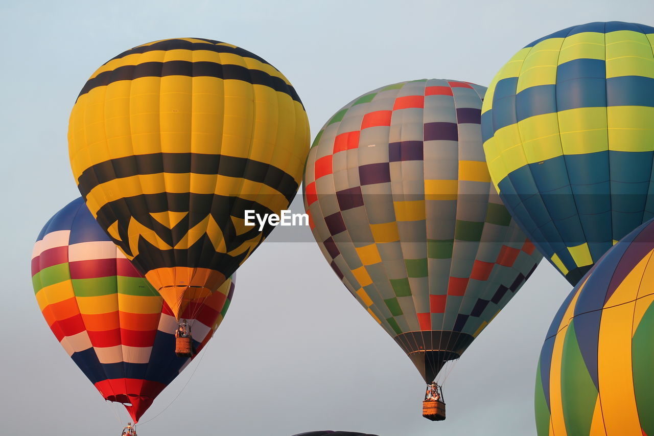 Low angle view of multi colored hot air balloons flying against clear sky