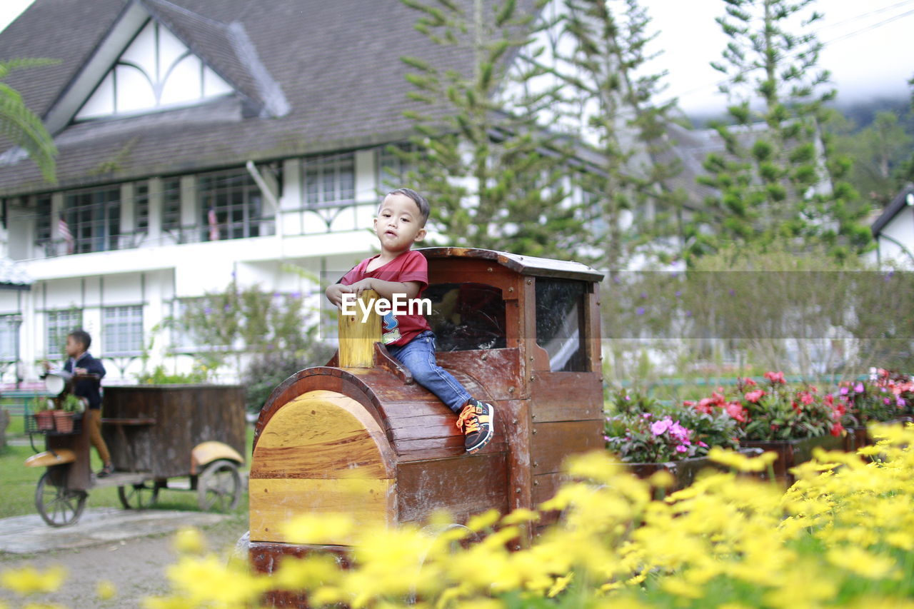 Full length portrait of baby boy playing on wooden train at park