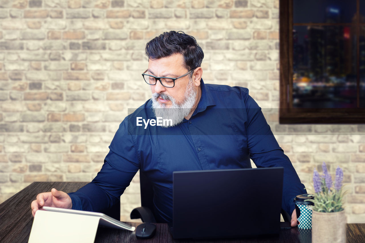 Stressed mixed race senior businessman at desk working late in office