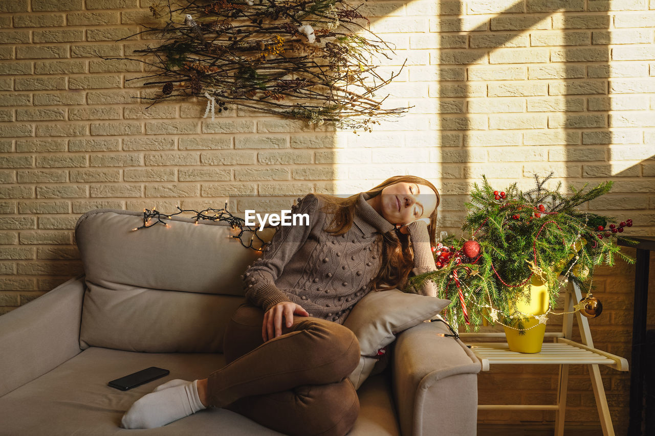 portrait of woman with dog sitting on sofa at home