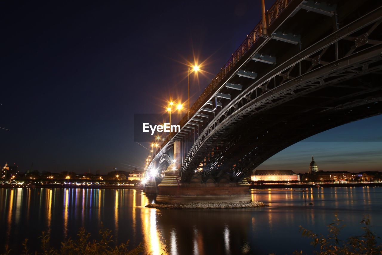 Illuminated heodor heuss bridge over rhine river at night