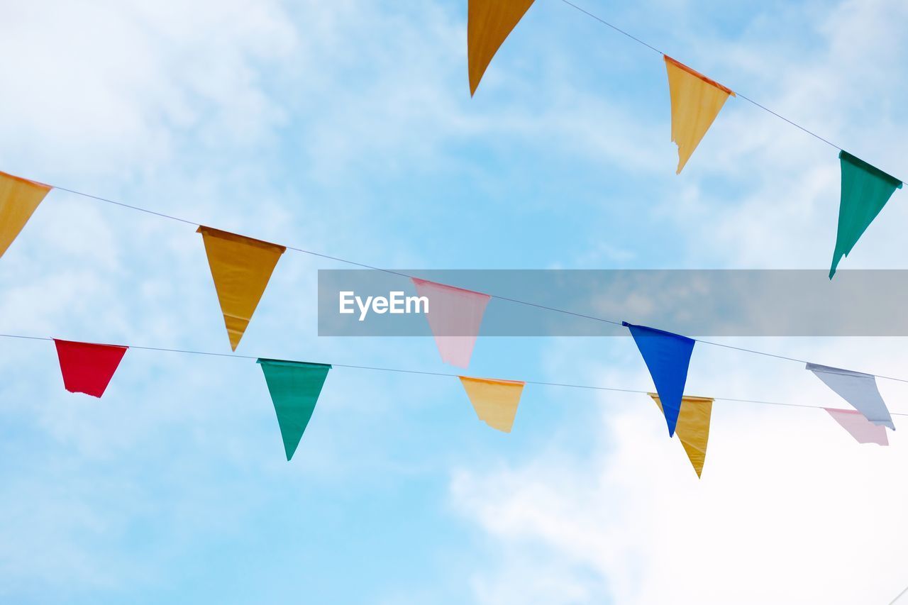 Low angle view of colorful buntings against blue sky