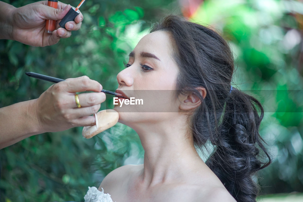 Close-up of person applying make-up on woman face