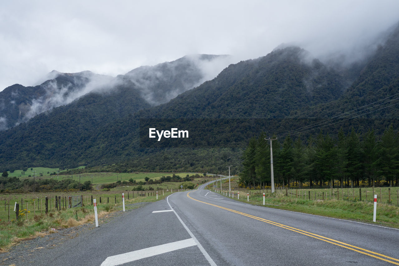 Scenic road in new zealand with mountains in background.