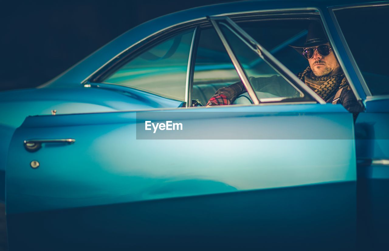 Portrait of man sitting in blue car