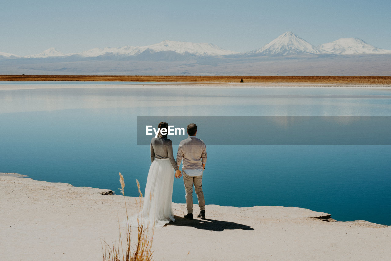 REAR VIEW OF PEOPLE ON THE SHORE