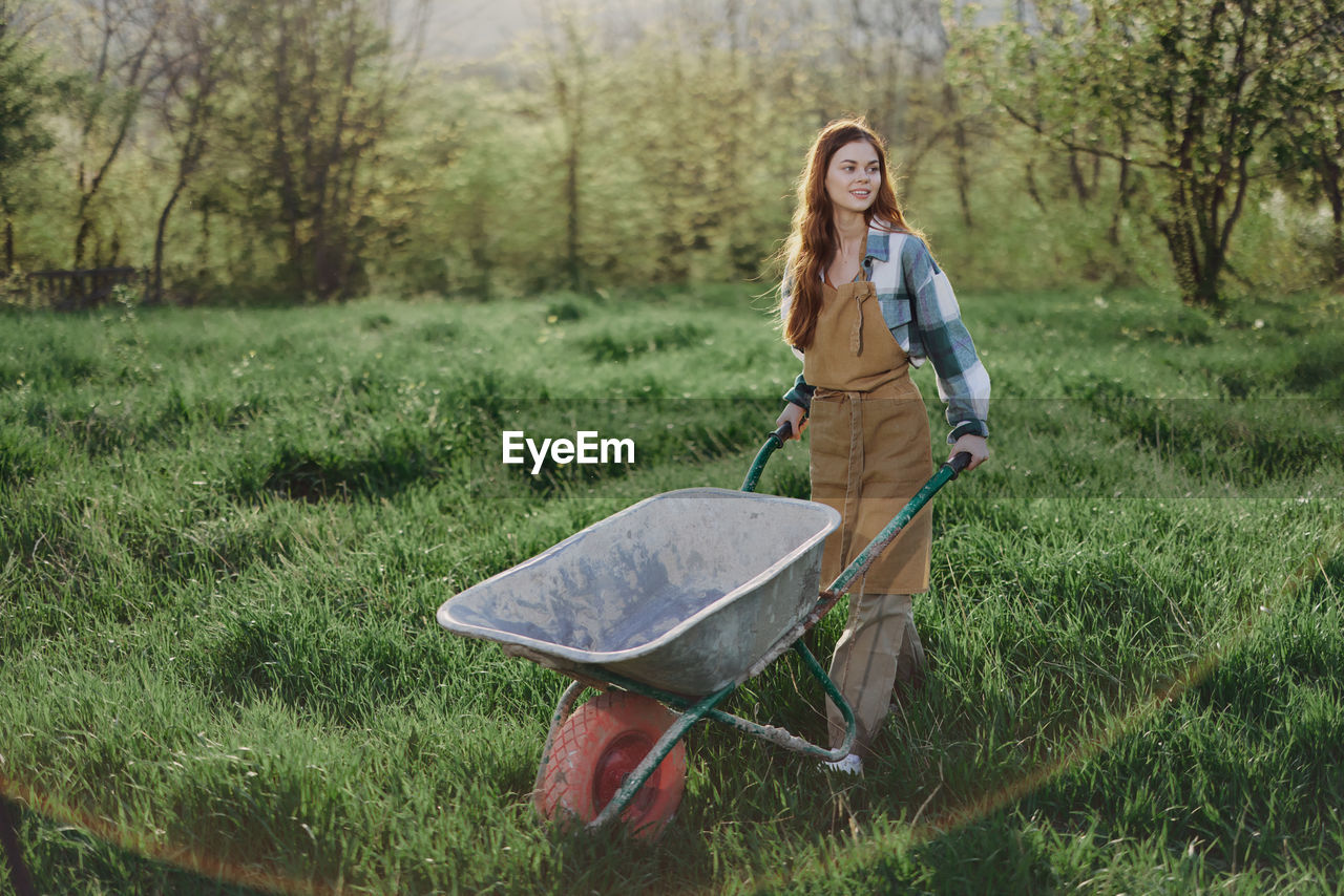 Young woman with wheelbarrow on grassland