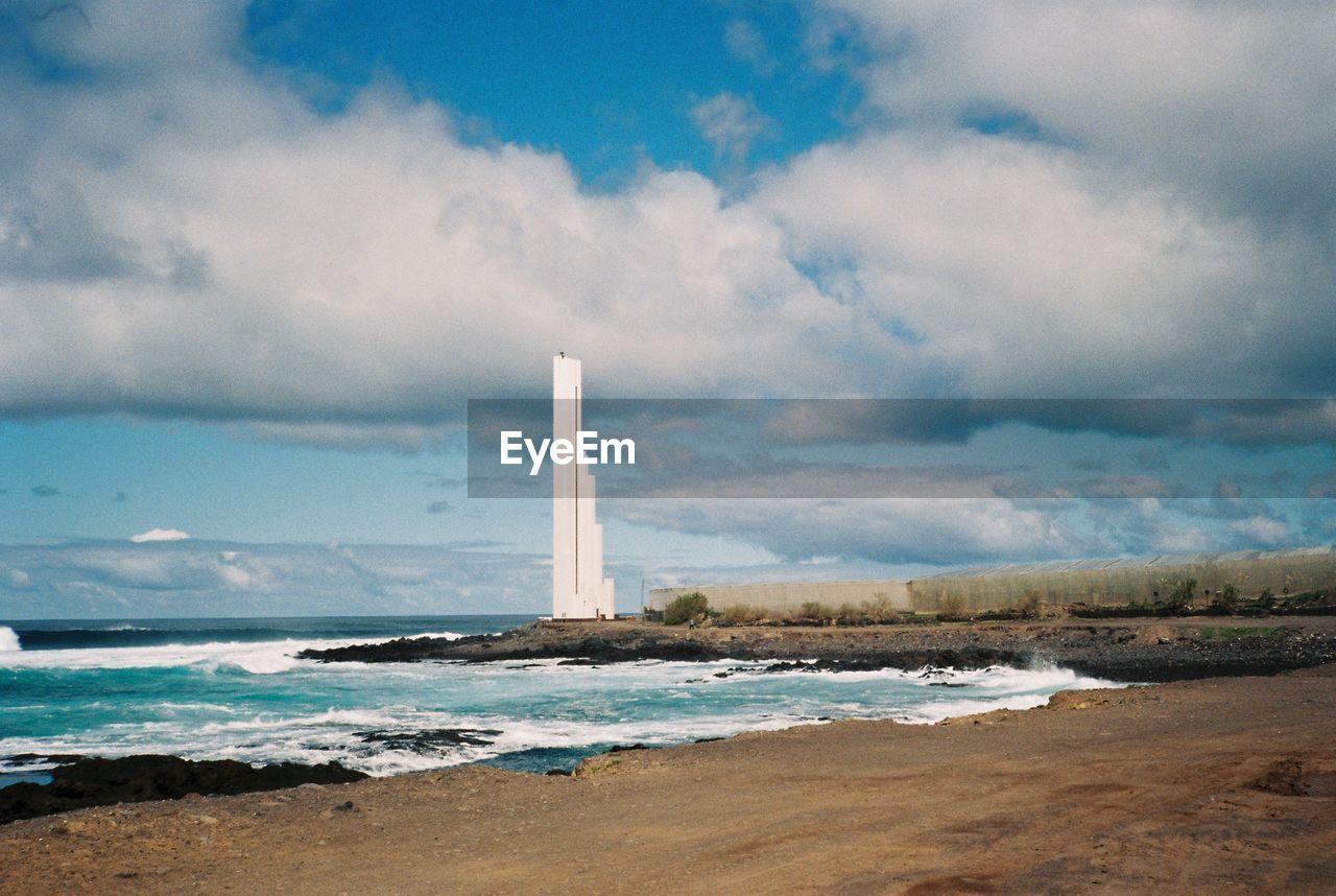 Lighthouse by sea against sky