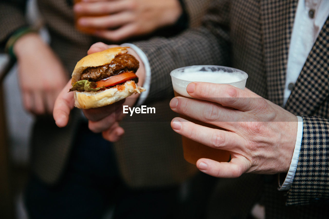 Close-up of man holding burger and beer