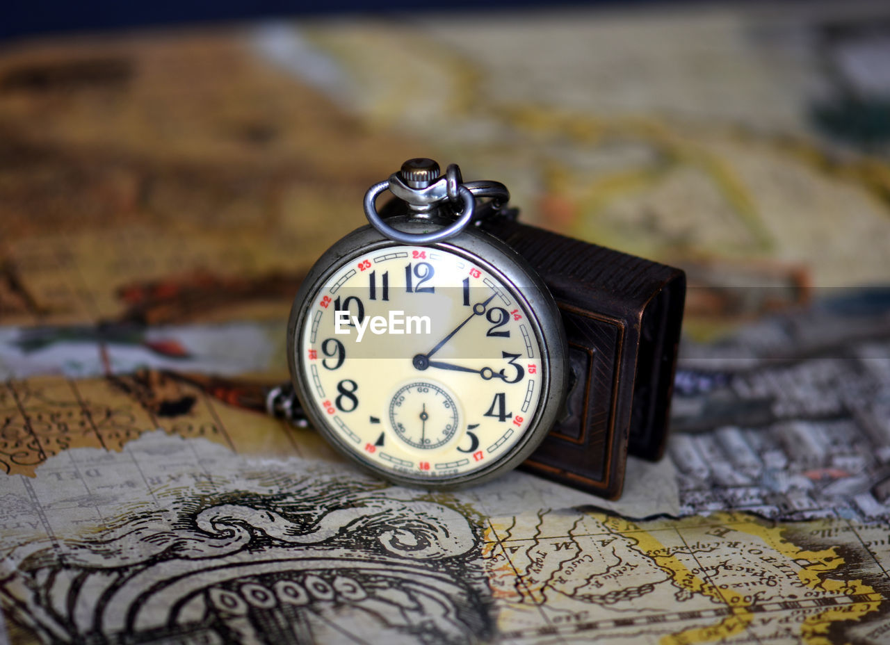 Close-up of pocket watch on map
