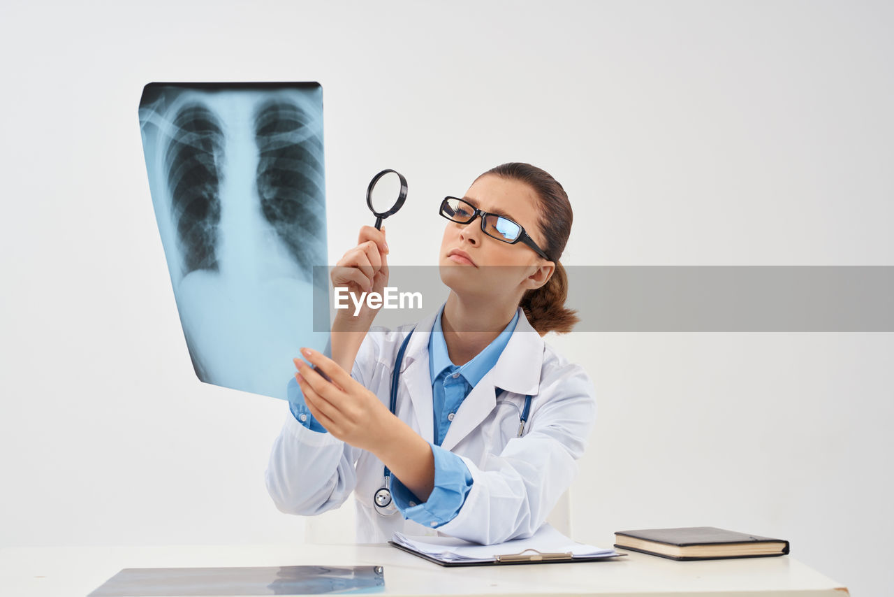 Doctor examining x-ray against white background