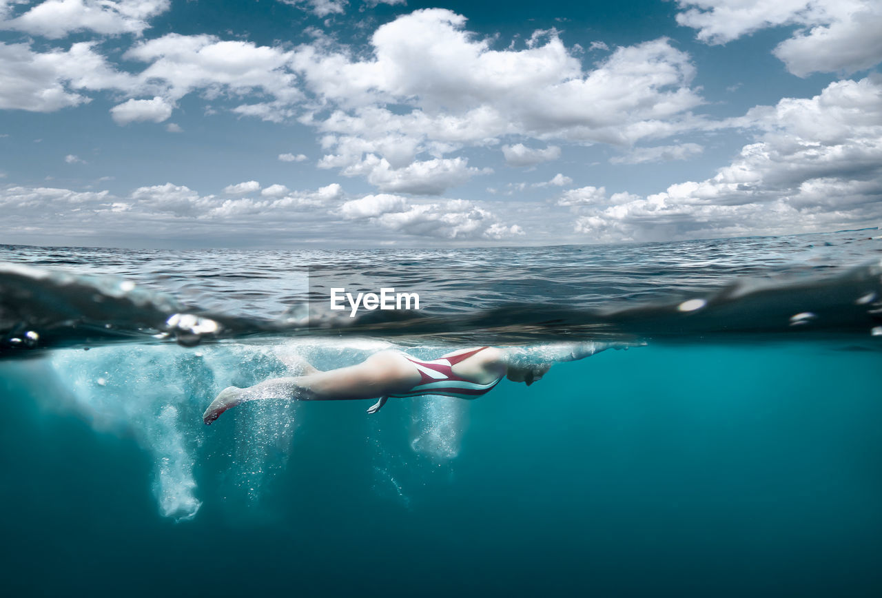 WOMAN SWIMMING IN POOL AGAINST SEA