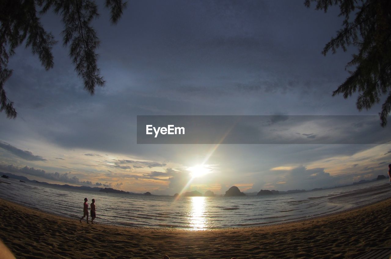 SILHOUETTE MAN ON BEACH AGAINST SKY AT SUNSET