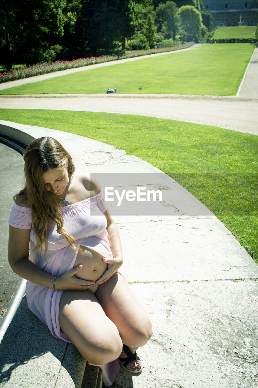 one person, women, sitting, full length, adult, grass, leisure activity, green, plant, day, nature, lifestyles, casual clothing, hairstyle, young adult, clothing, relaxation, sunlight, person, emotion, high angle view, lawn, female, looking, activity, long hair, outdoors, footwear, park - man made space, child, park, shadow, human leg, summer, blond hair