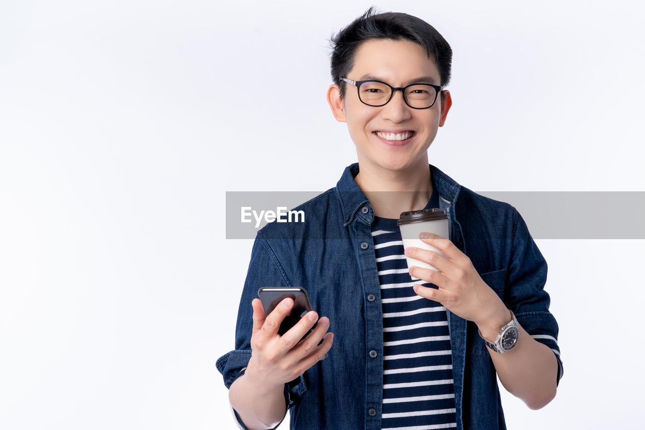 PORTRAIT OF SMILING YOUNG MAN HOLDING CAMERA