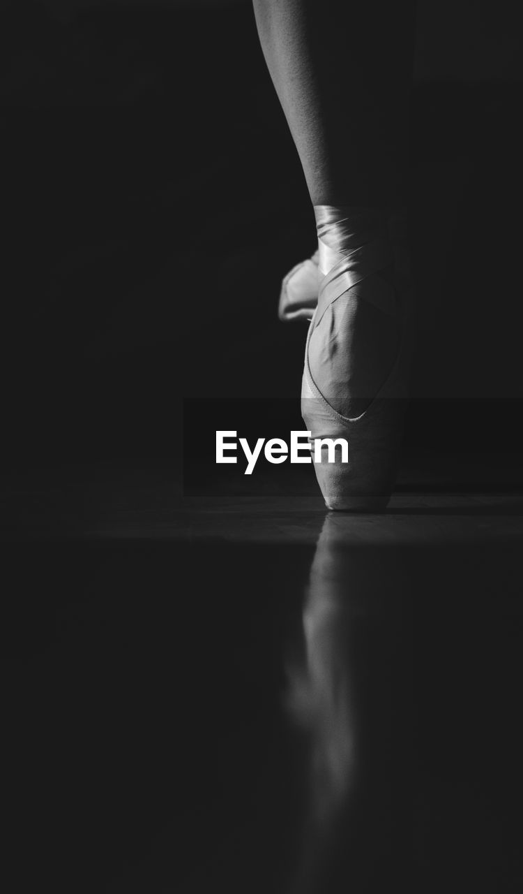 Low section of ballerina balancing on toe against black background