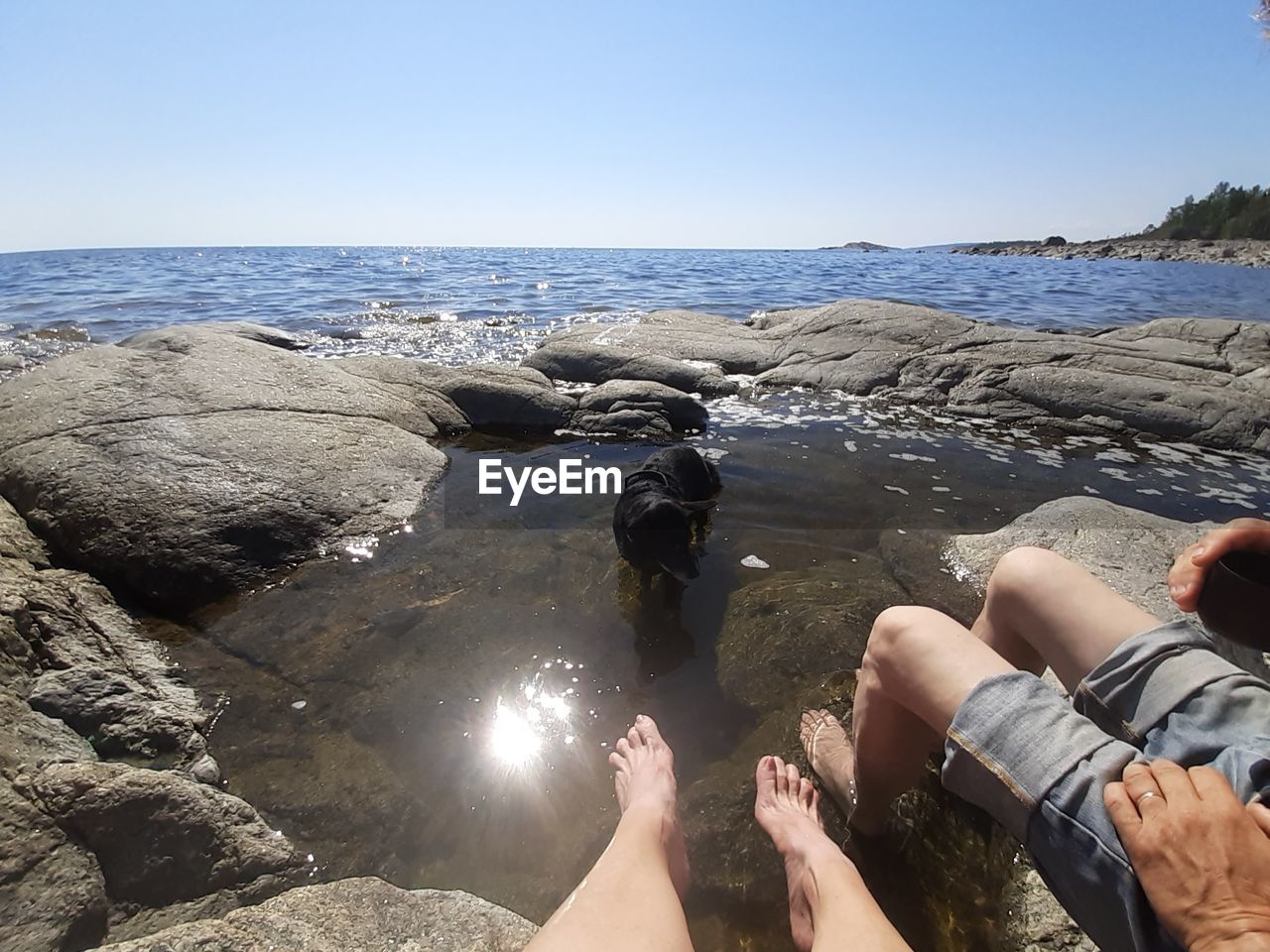 LOW SECTION OF PEOPLE ON ROCKS AT BEACH