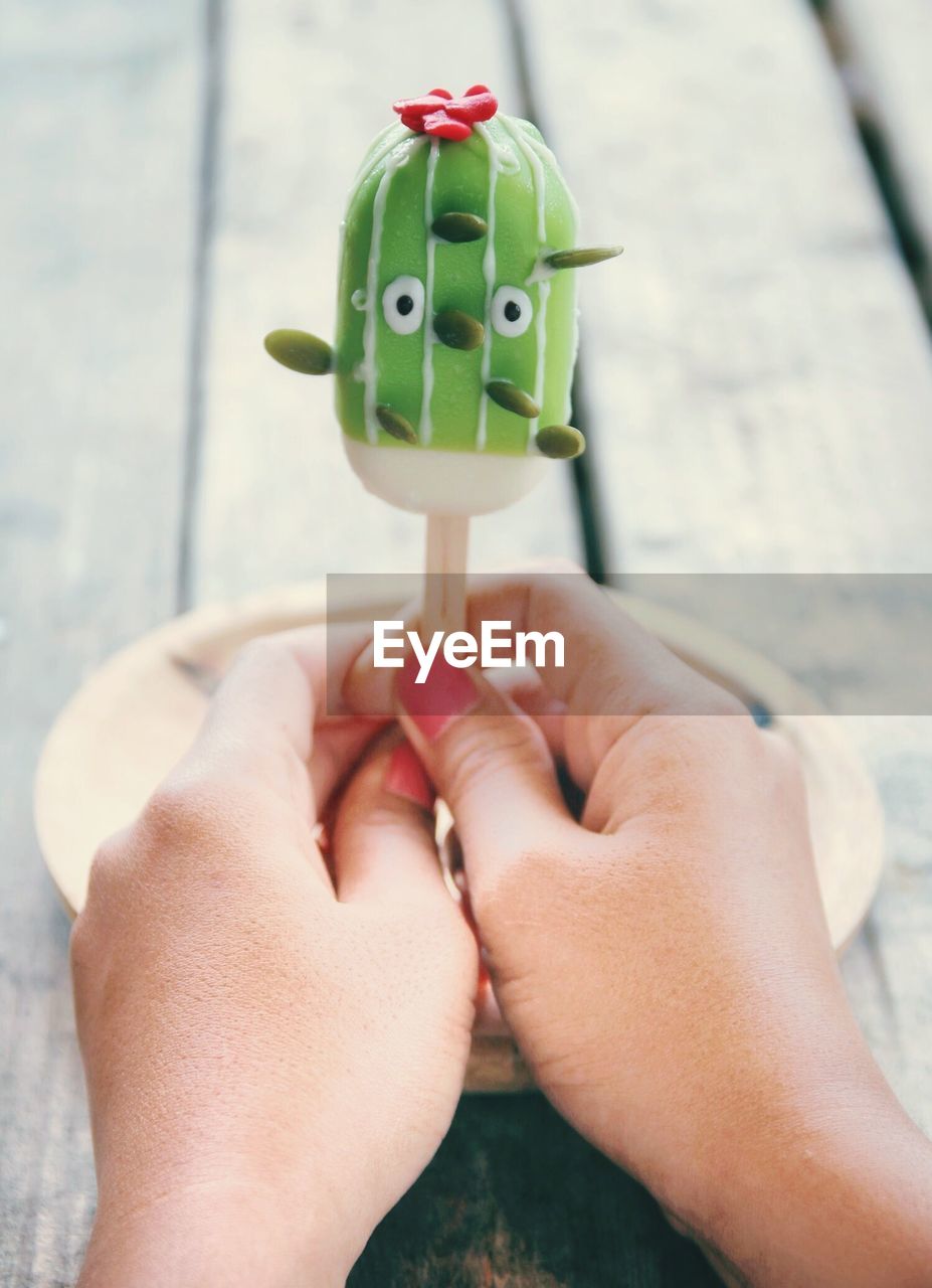 Cropped hands of woman holding ice cream on table