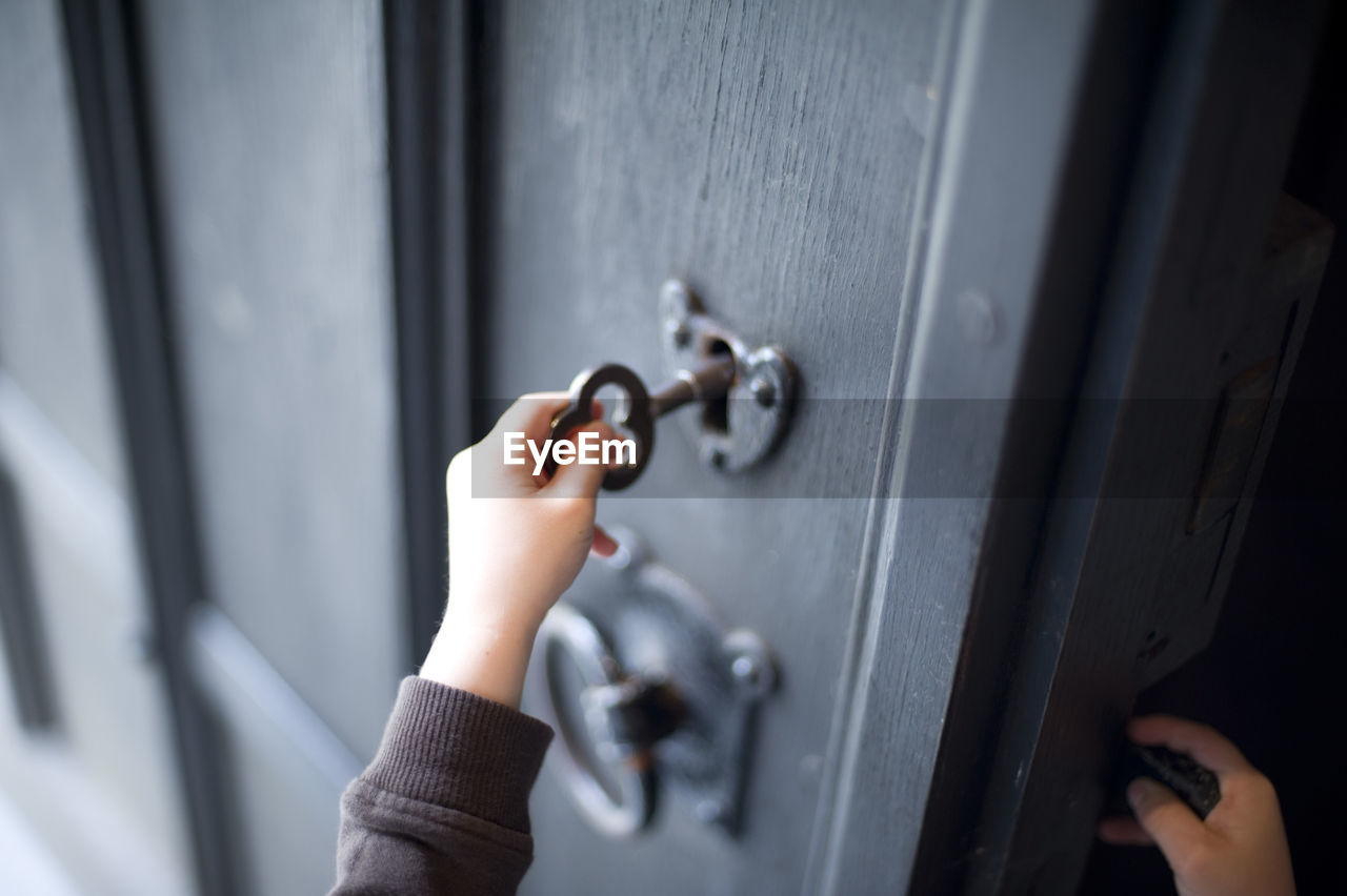 Cropped hand of child unlocking door at home