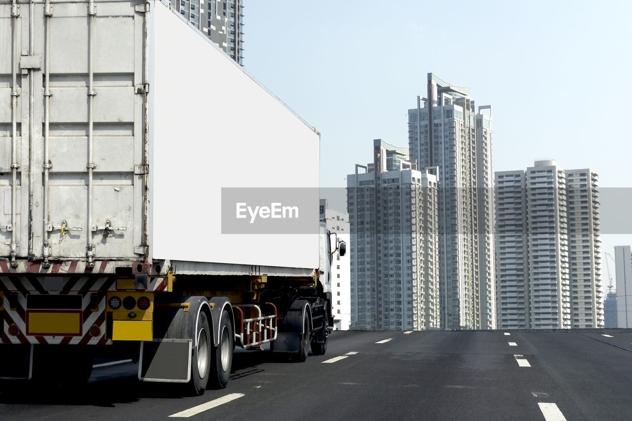 ROAD AMIDST BUILDINGS IN CITY AGAINST SKY