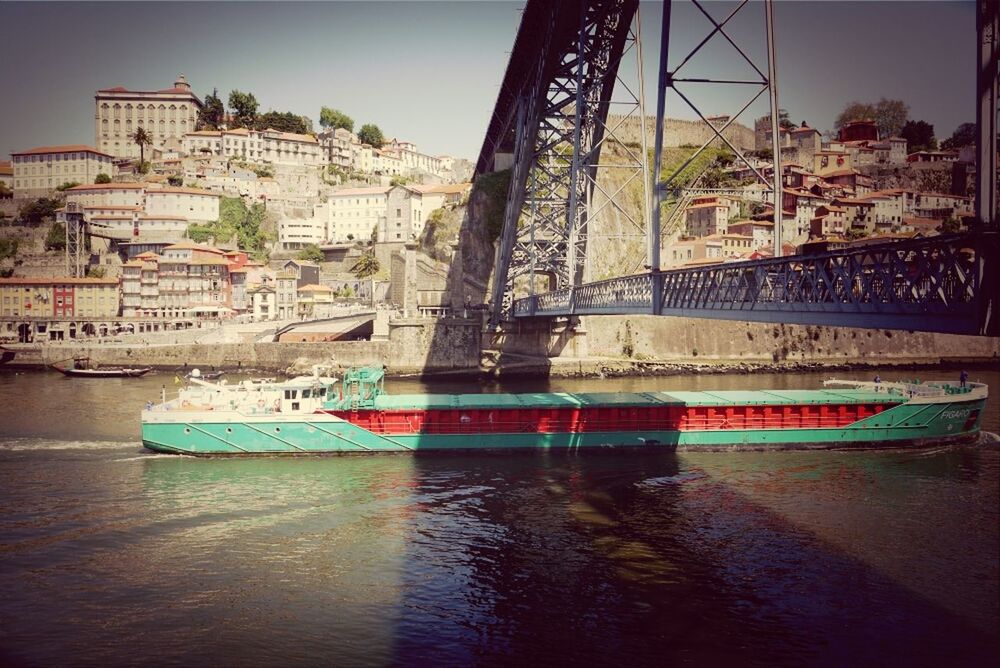 BOATS MOORED IN RIVER WITH CITY IN BACKGROUND