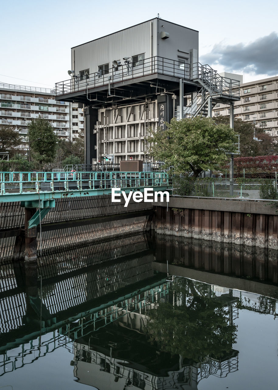 REFLECTION OF BRIDGE ON LAKE AGAINST BUILDINGS