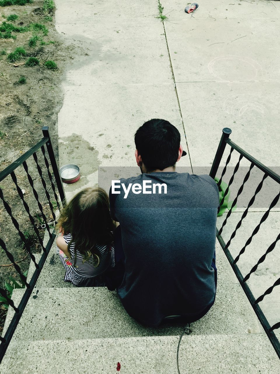 Rear view of man sitting with daughter on steps