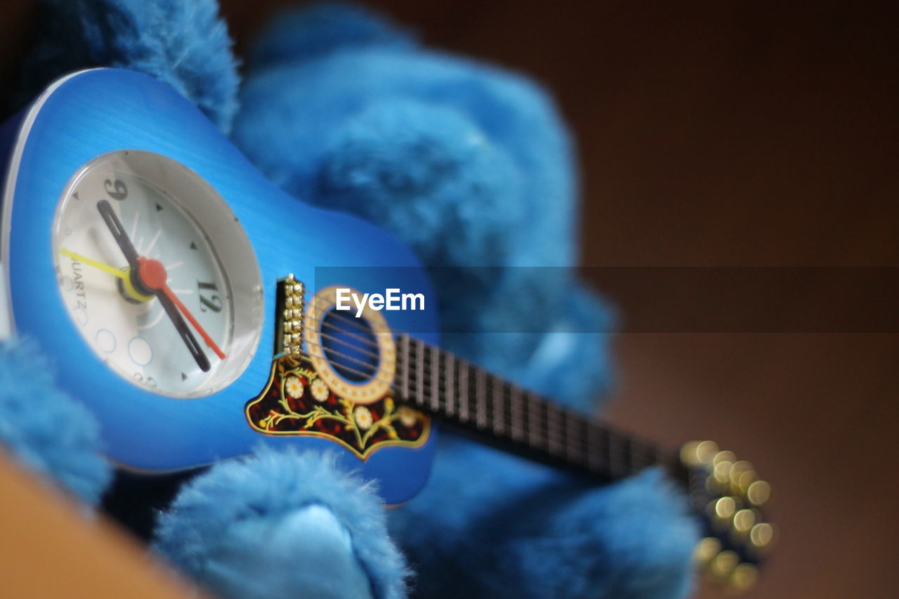 Low angle view of toy guitar clock and teddy bear against black background