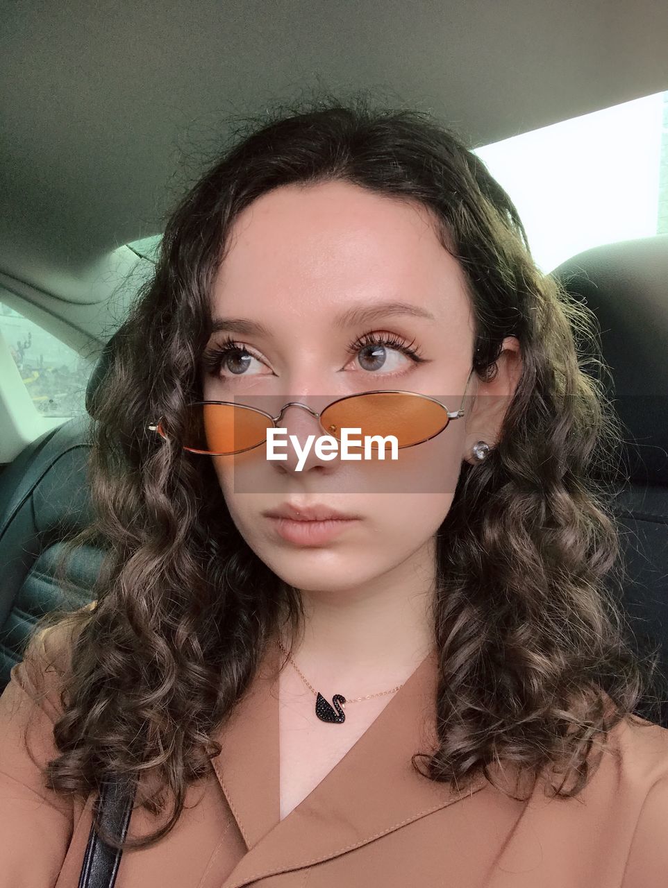 PORTRAIT OF YOUNG WOMAN IN CAR WITH EYEGLASSES