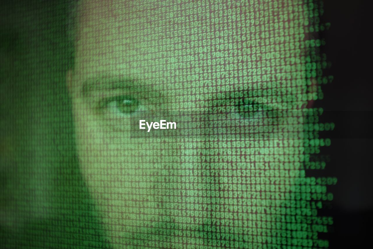 Man's face reflected in computer screen with binary code