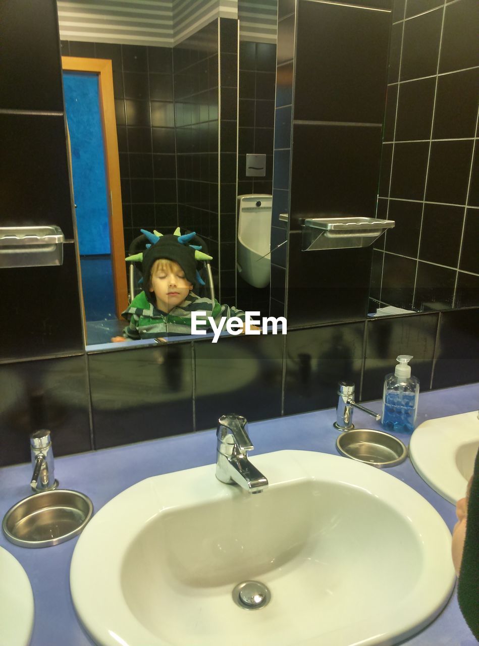 Boy reflecting on mirror in bathroom
