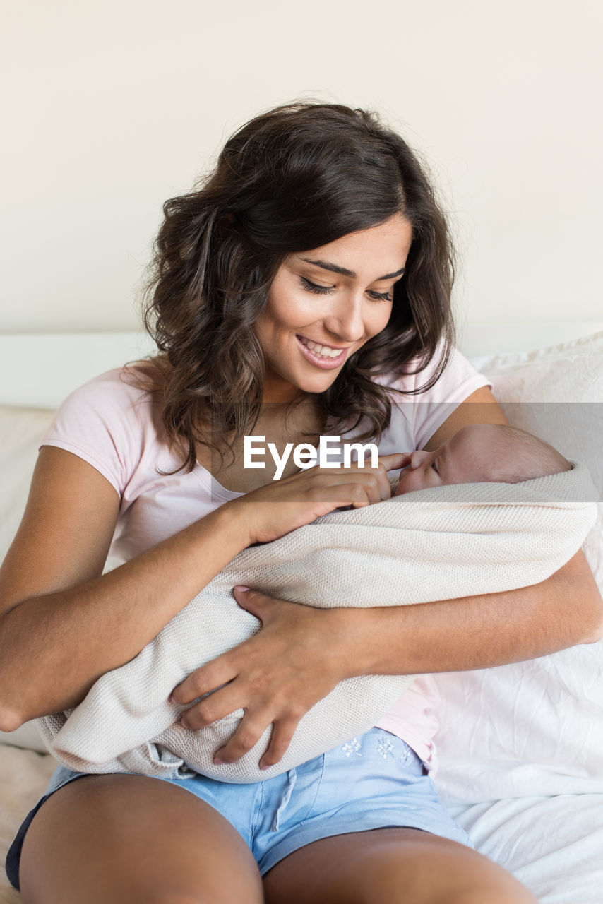 Smiling mother looking at son while sitting on sofa at home