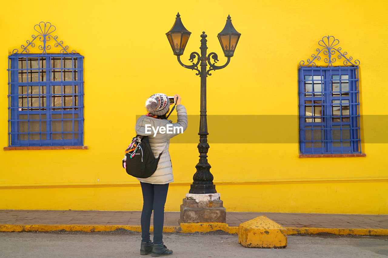 Traveler taking photos of an eye-catching vintage streetlamp with vivid colored building