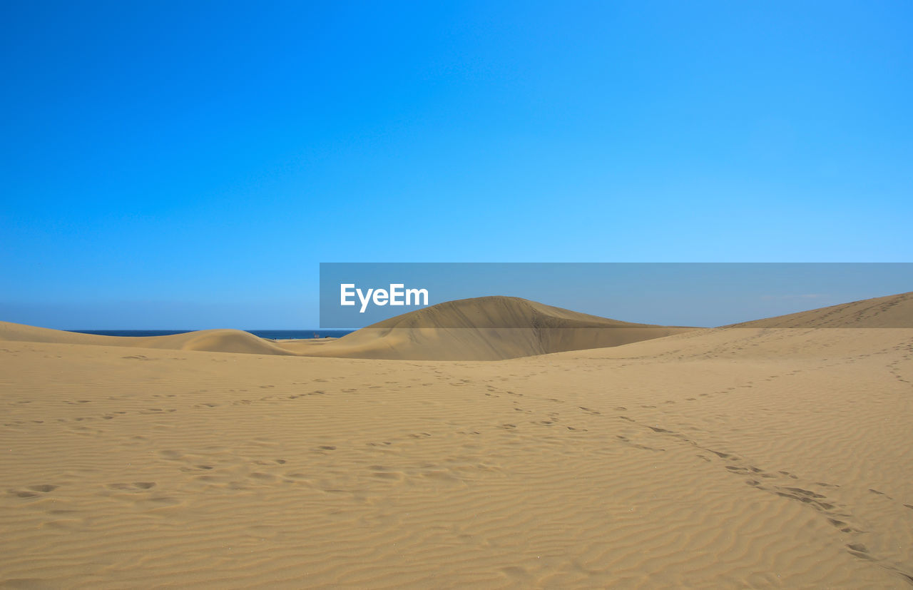 Scenic view of desert against clear blue sky