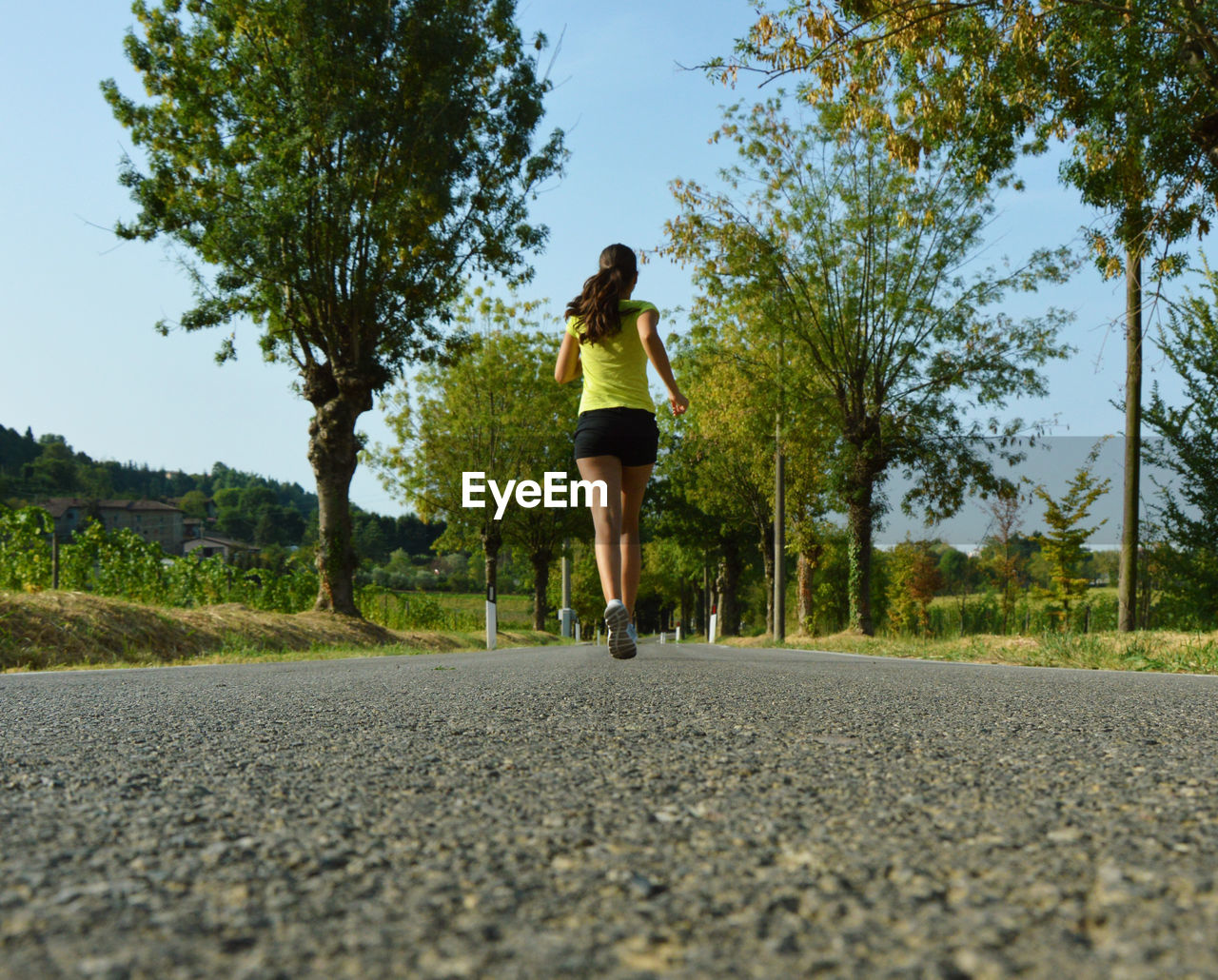 Rear view of young woman running on road against sky