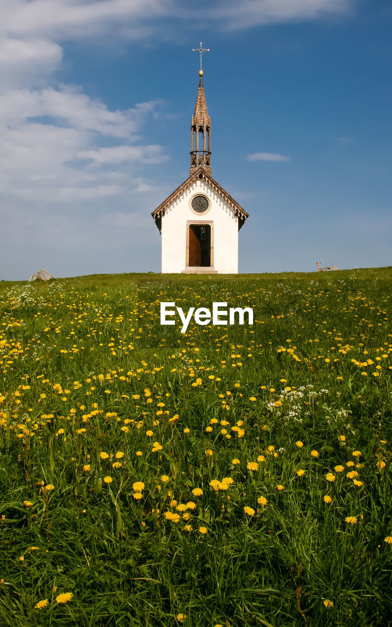 View of little chapel on field against cloudy sky