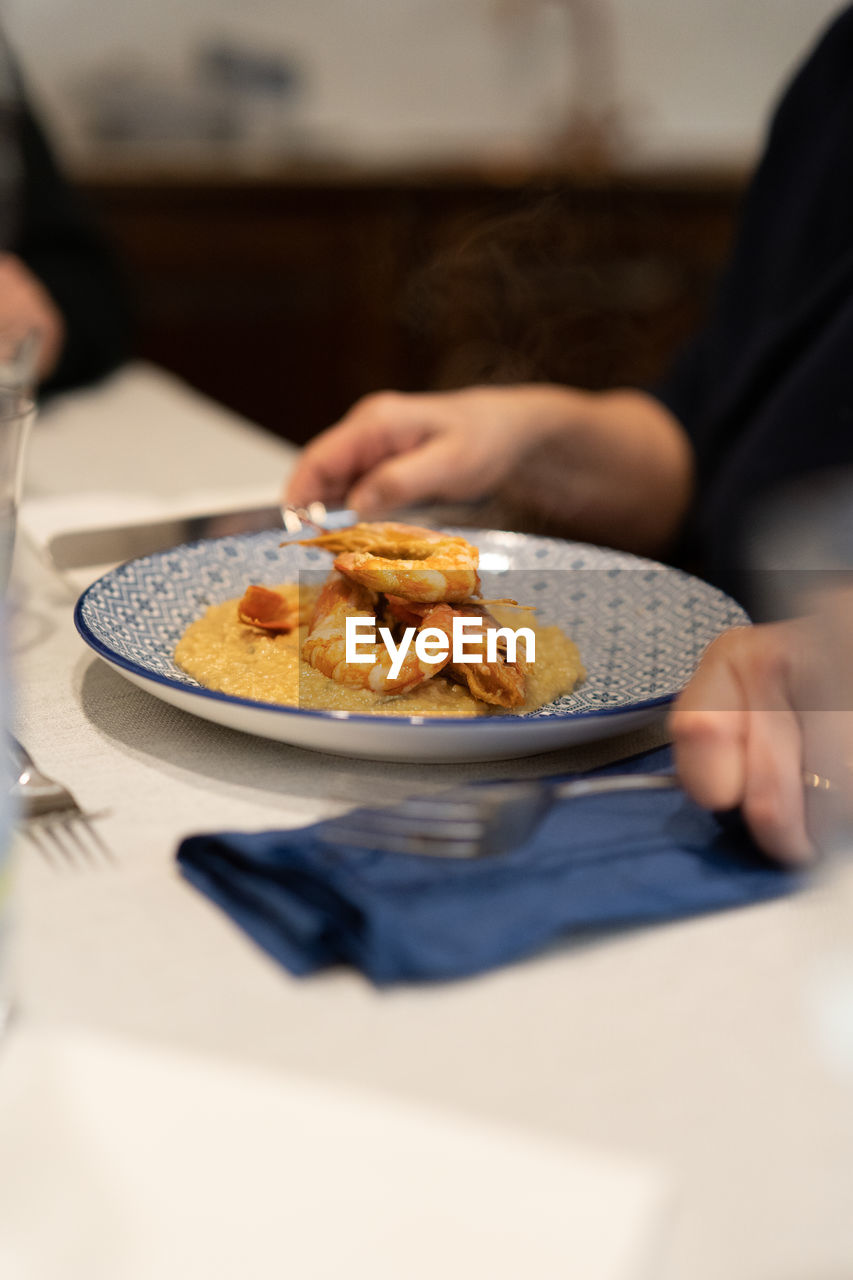 Midsection of person holding food in plate on table