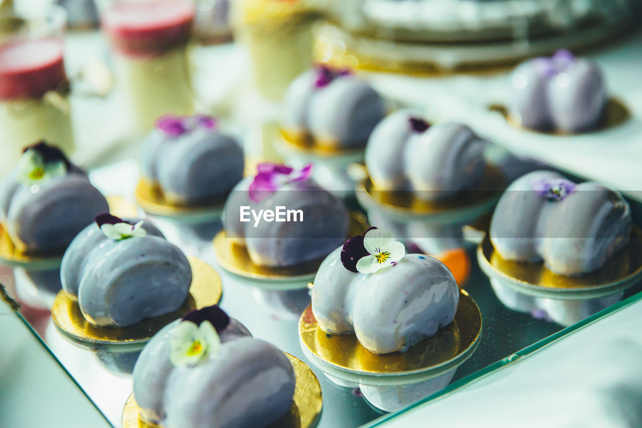 Purple mousse cakes on a mirrored tray, decorated with a violet flower