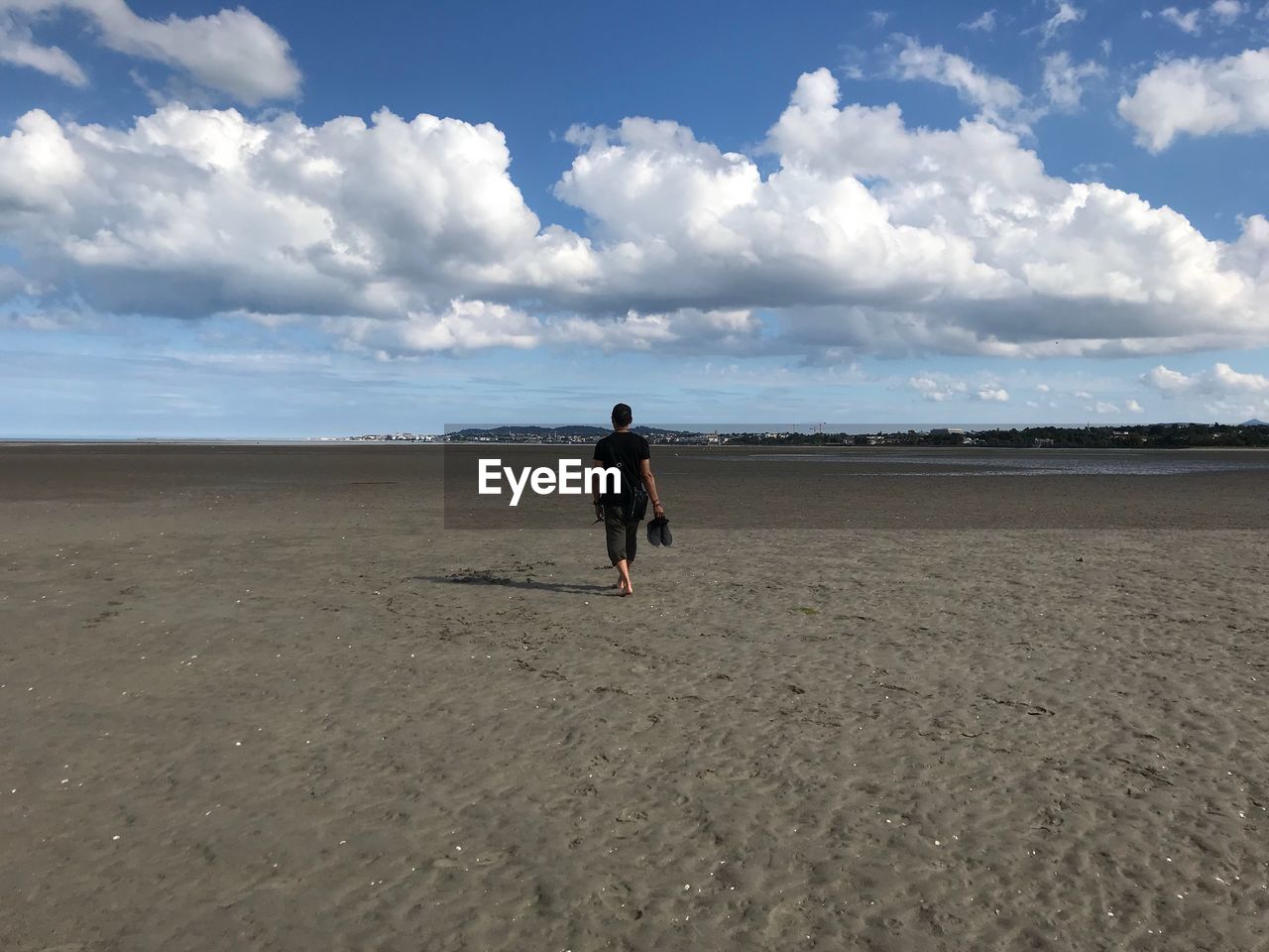 Rear view of woman at beach against sky