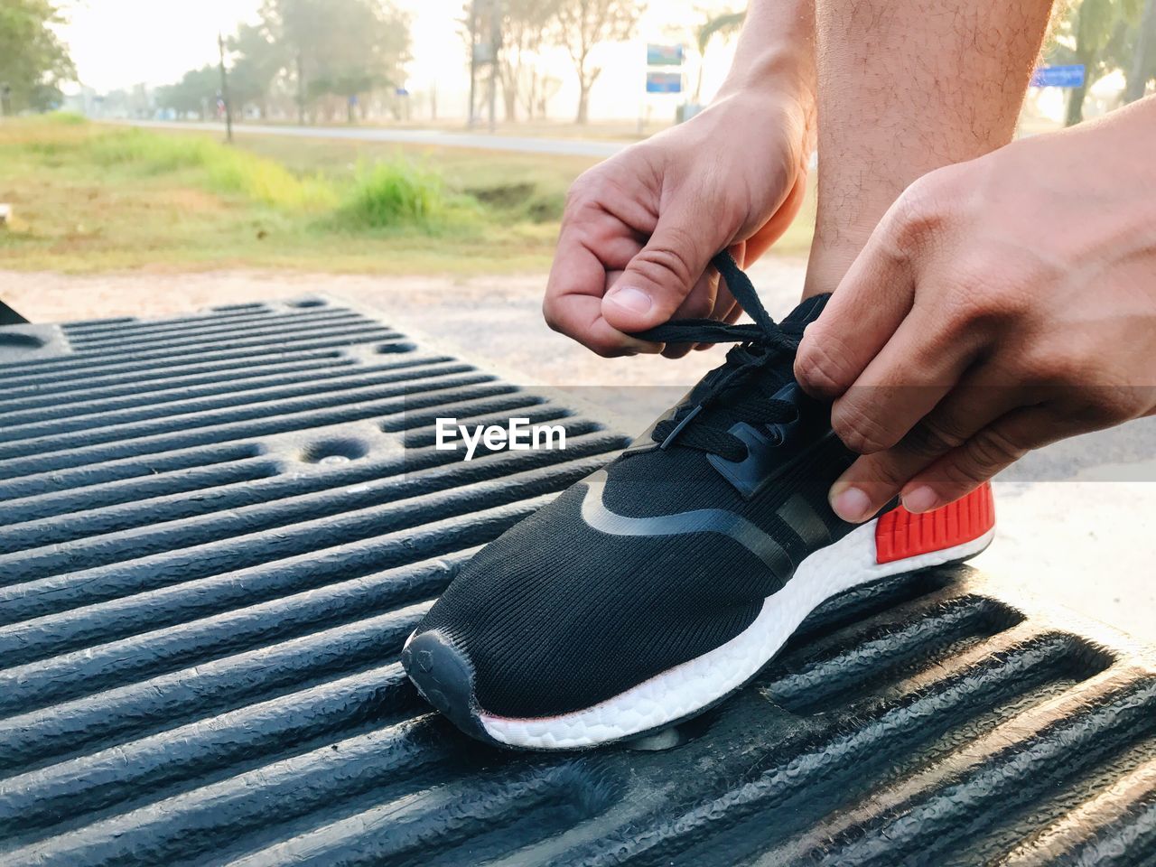 Low section of man tying shoelace outdoors