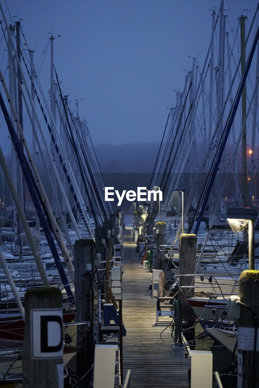 Sailboats on pier by sea against clear sky