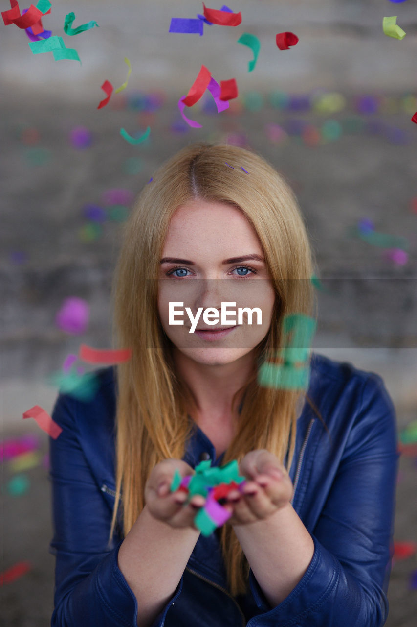 Portrait of smiling young woman holding confetti