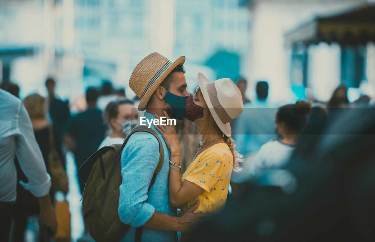 Side view of couple wearing mask kissing outdoors